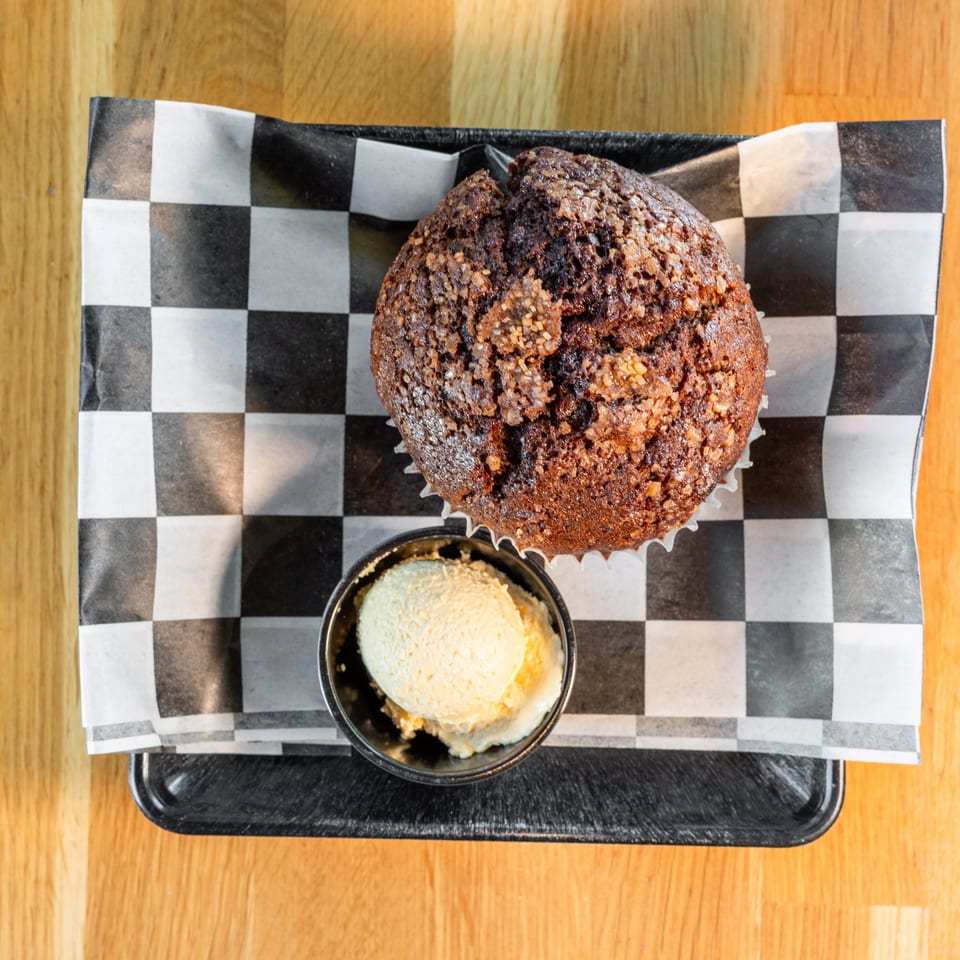Overhead view of a chocolate muffin with sugar topping and a scoop of vanilla ice cream.
